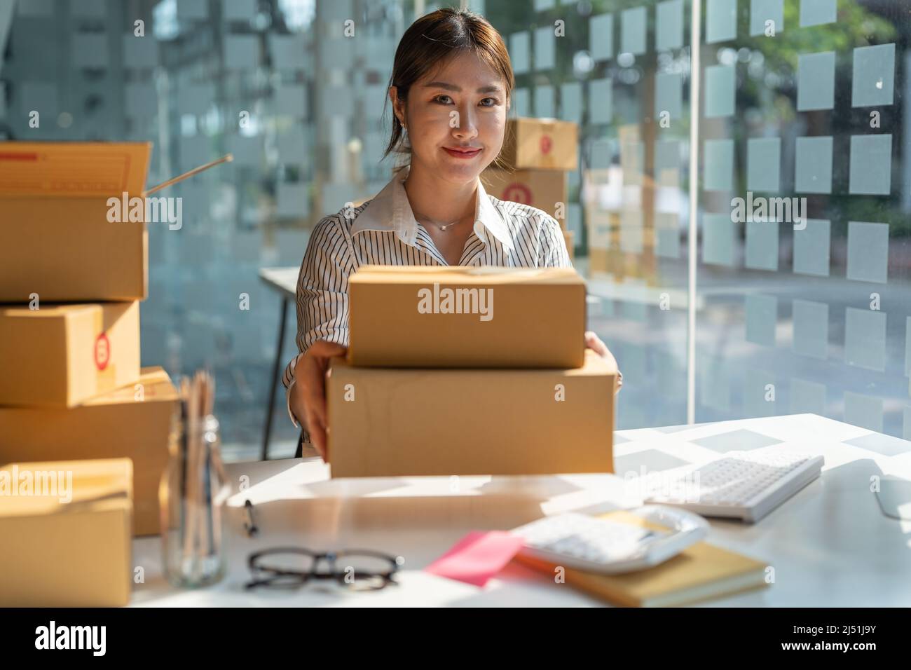 Junger asiatischer Kleinunternehmen, der im Heimbüro arbeitet und die Bestellungen zur Kenntnis nimmt. Online-Marketing Verpackung Lieferung, Startup KMU Unternehmer Stockfoto