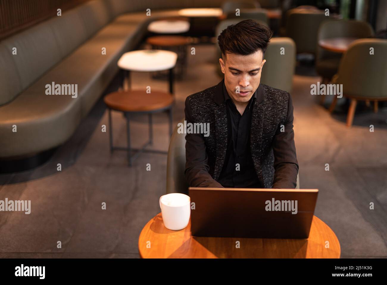 Junger Geschäftsmann, der im Café einen Laptop benutzt Stockfoto