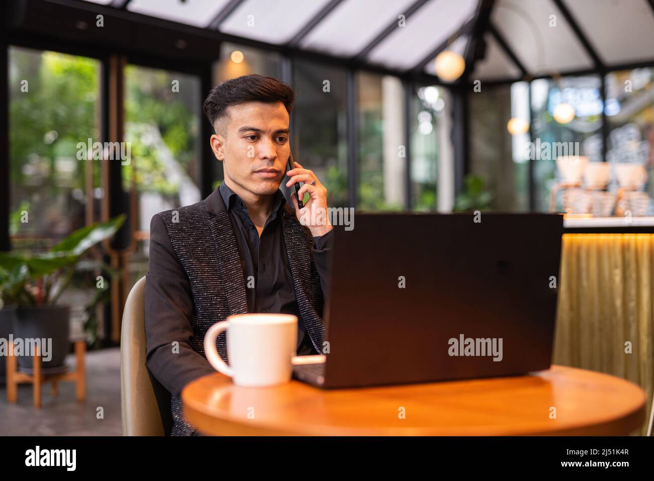 Junger Geschäftsmann, der im Café einen Laptop benutzt Stockfoto