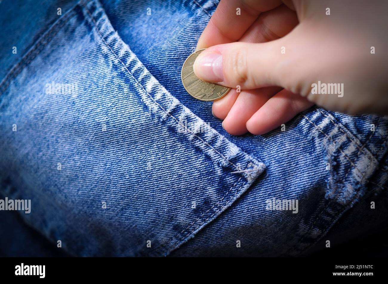 Hand legt Goldmünze Wechsel in Jeans Tasche Geld Konzept Stockfoto