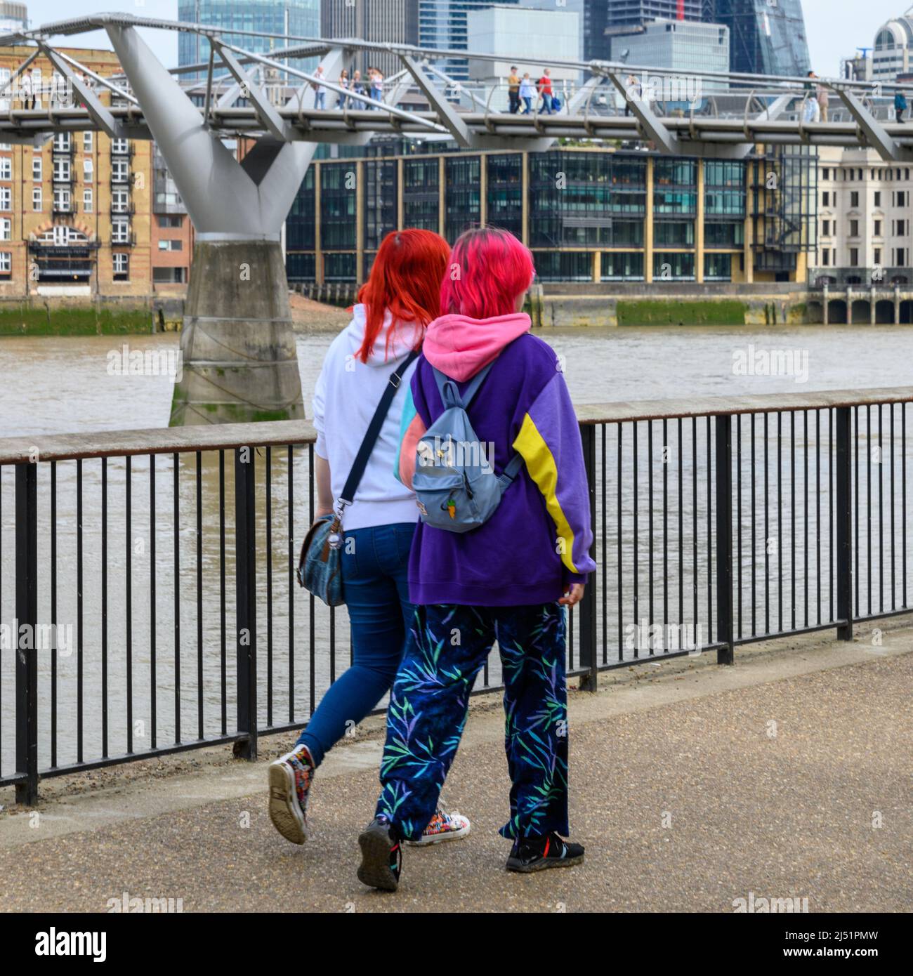 Zwei junge Frauen mit gefärbten roten Haaren und farbenfroher Kleidung, South Bank, London, Großbritannien, April Stockfoto