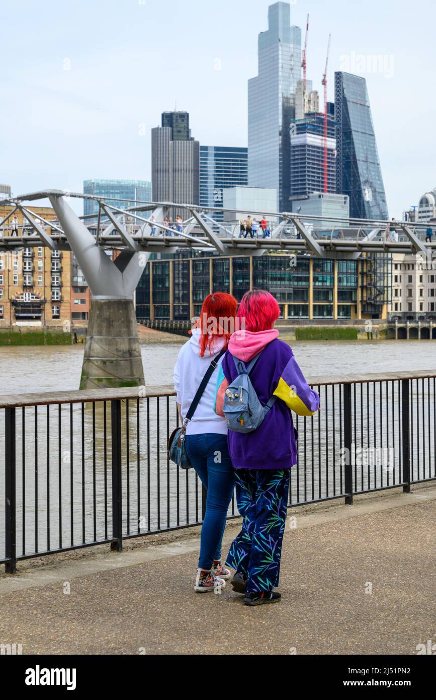 Zwei junge Frauen mit gefärbten roten Haaren und farbenfroher Kleidung, South Bank, London, Großbritannien, April Stockfoto