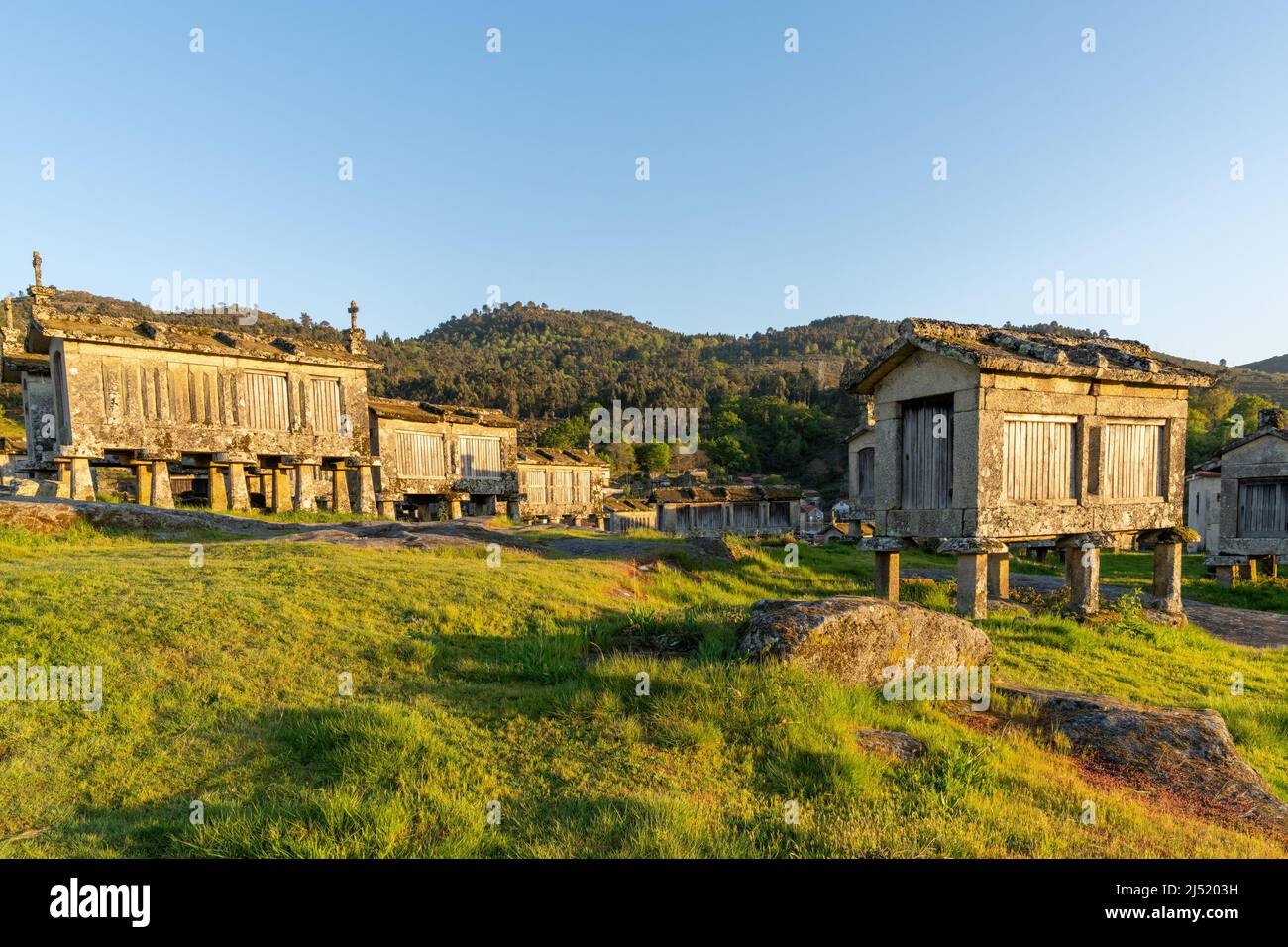 Warmes Abendlicht über Getreidespeicher und Steinschuppen im Dorf Lindoso in Portugal Stockfoto