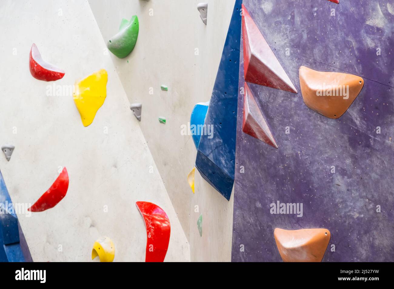 Steinhaken oder Griffe an der künstlichen Kletterwand in der Boulderhalle. Stockfoto