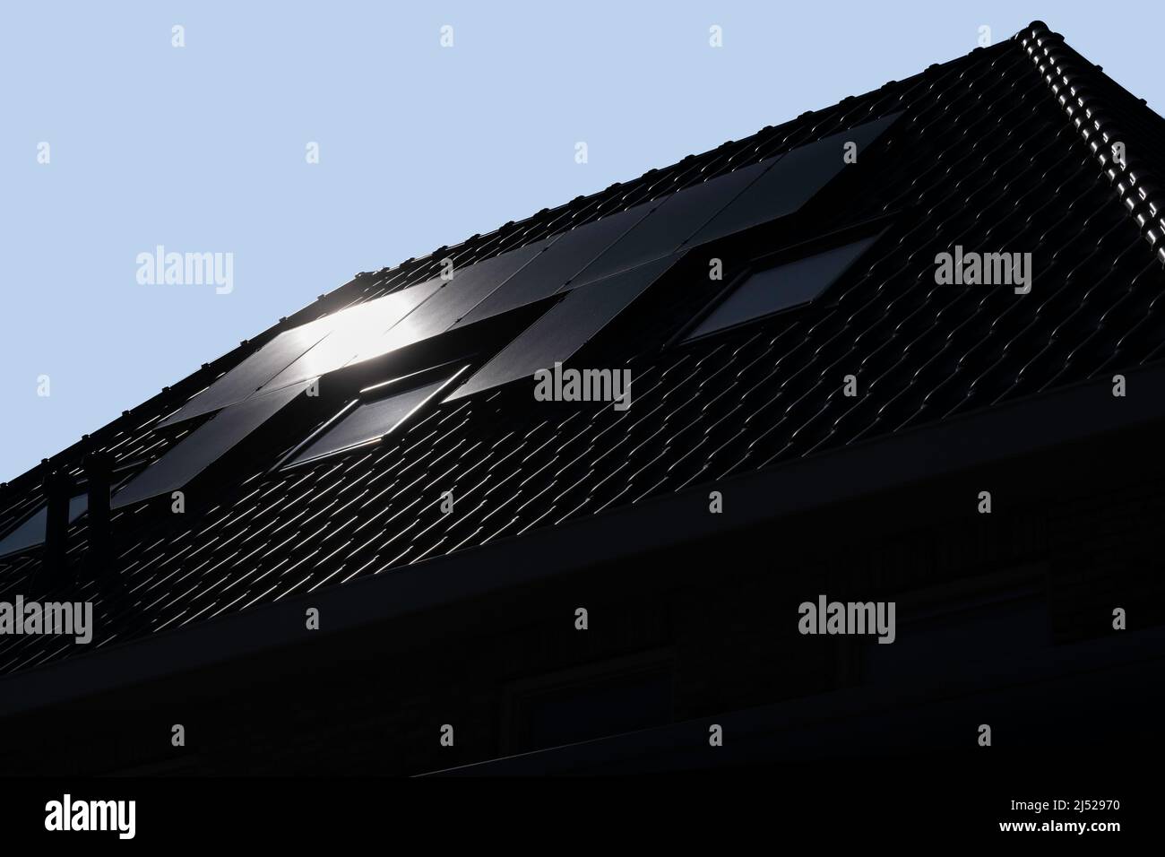Sonnenkollektoren, die auf den Dächern eines modernen Neubaus in einer Straße in den Niederlanden mit Sonne und blauem Himmel montiert sind. Nachhaltige Energie. Für Text platzieren Stockfoto