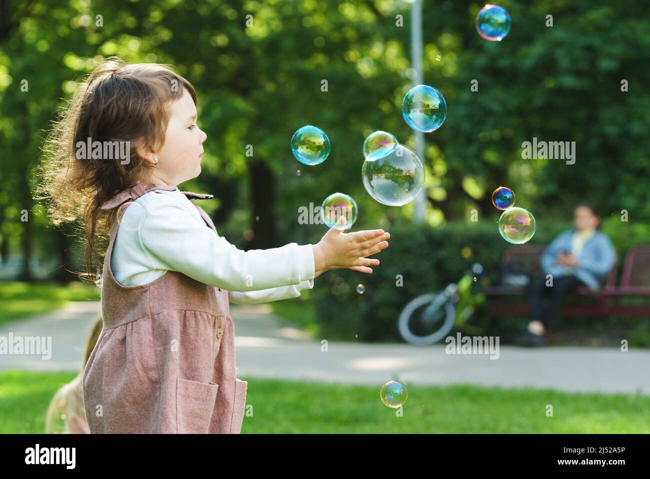 Nettes kleines Mädchen fangen Seifenblasen in einem Stadtpark Stockfoto