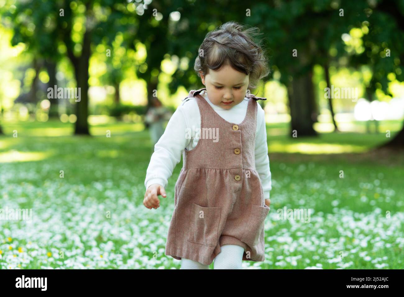 Kindheit und Sorgenfreiheit. Nettes kleines Mädchen geht in einem Stadtpark. Stockfoto