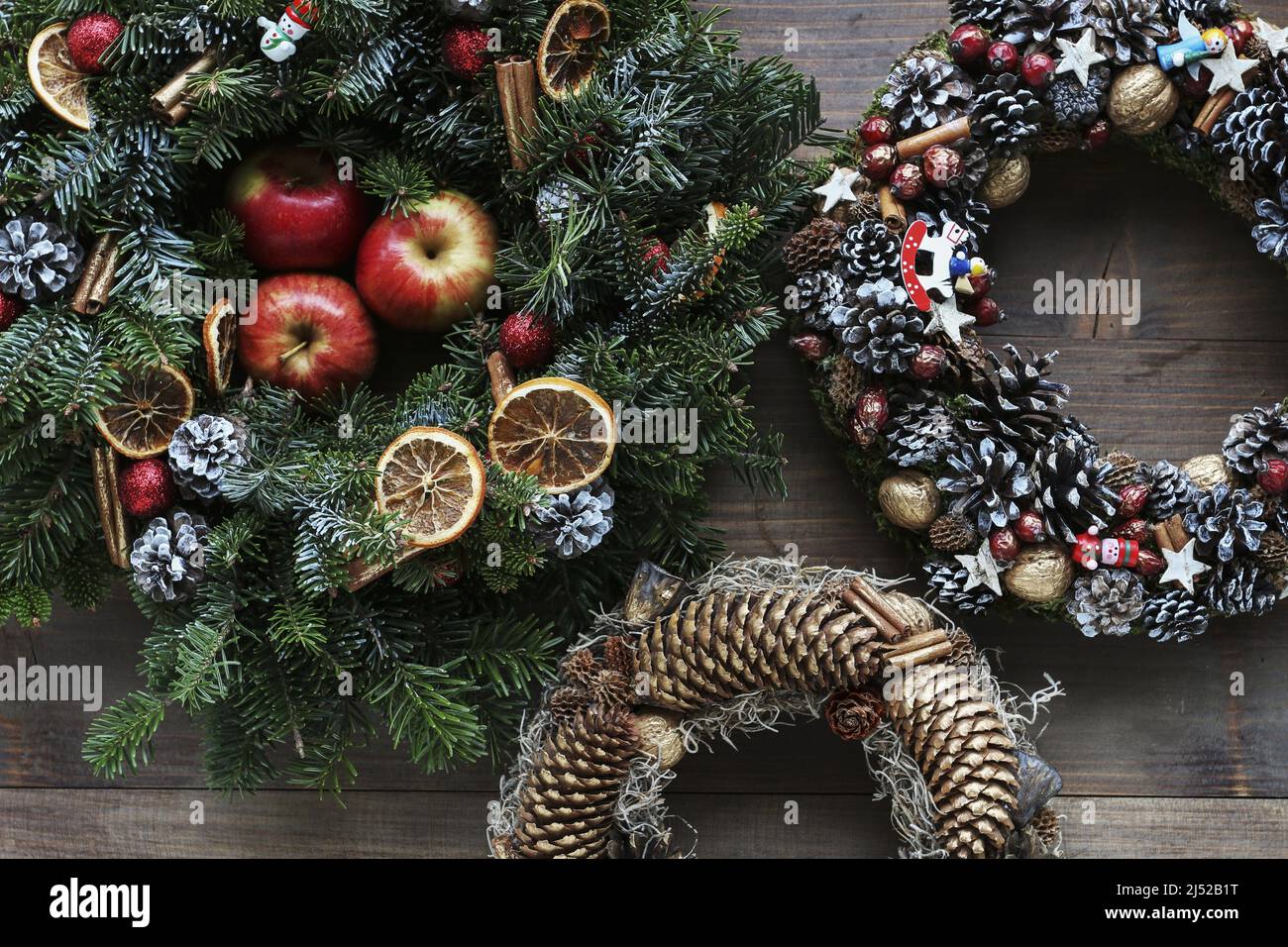 Drei verschiedene traditionelle Weihnachtskränze auf Holzhintergrund. Festliche Einrichtung Stockfoto