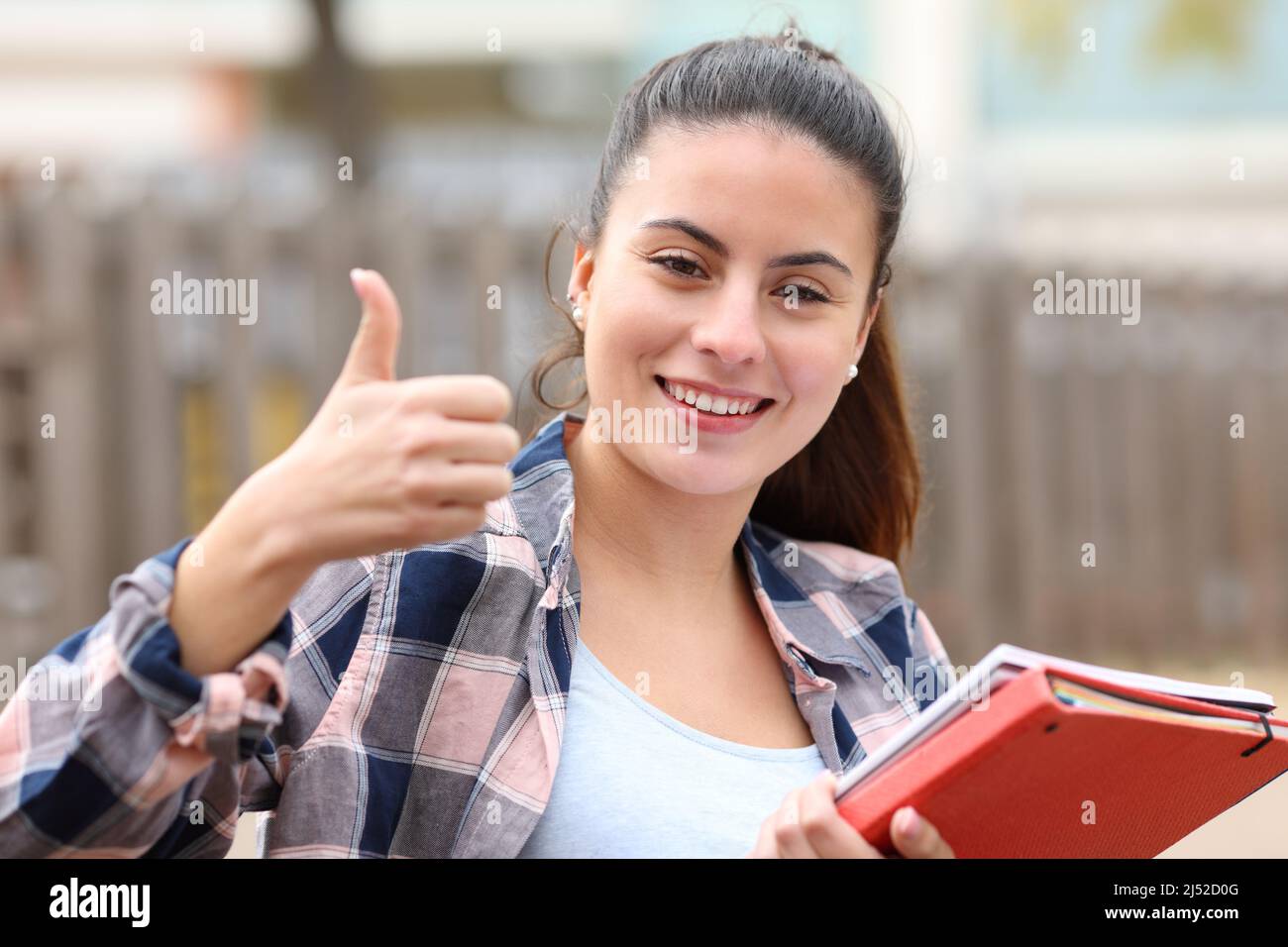 Vorderansicht Porträt eines glücklichen Studenten, der Daumen nach oben in einem Park gestikuliert Stockfoto