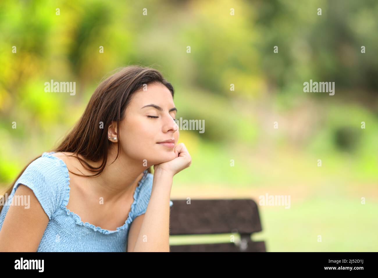 Entspannter Teenager, der auf einer Bank in einem Park sitzt Stockfoto