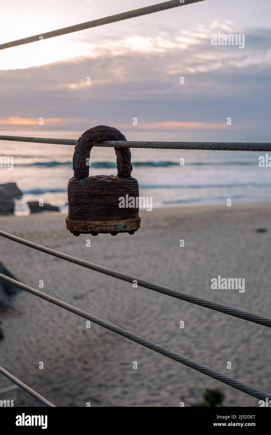 Das alte rostige masterlock hängt an einem Geländer auf der Treppe hinunter zum Garapatta State Beach Stockfoto