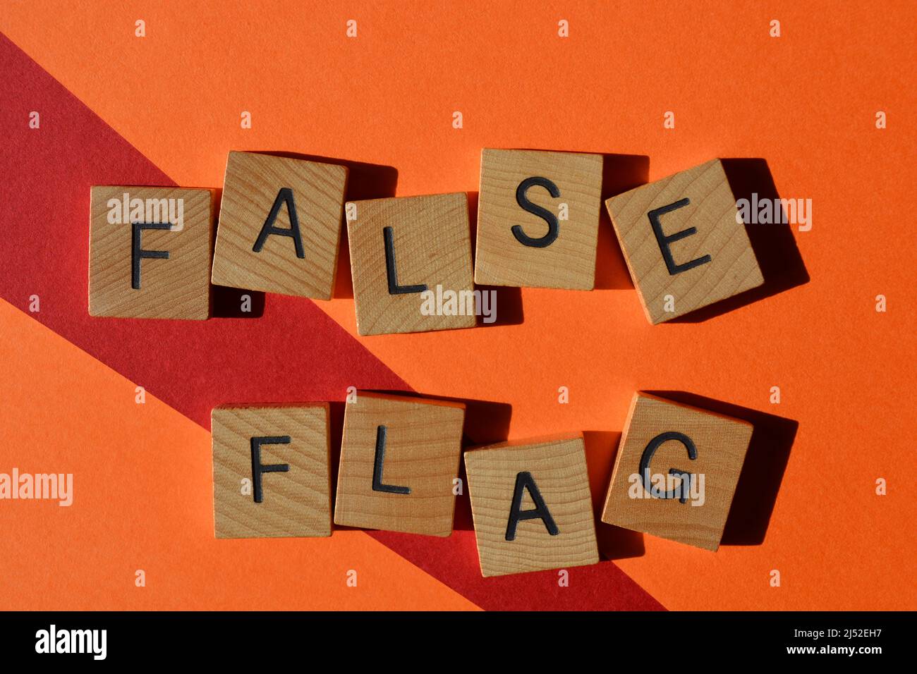Falsche Flagge, Wörter in Holzbuchstaben isoliert auf hellrotem und orangefarbenem Hintergrund Stockfoto