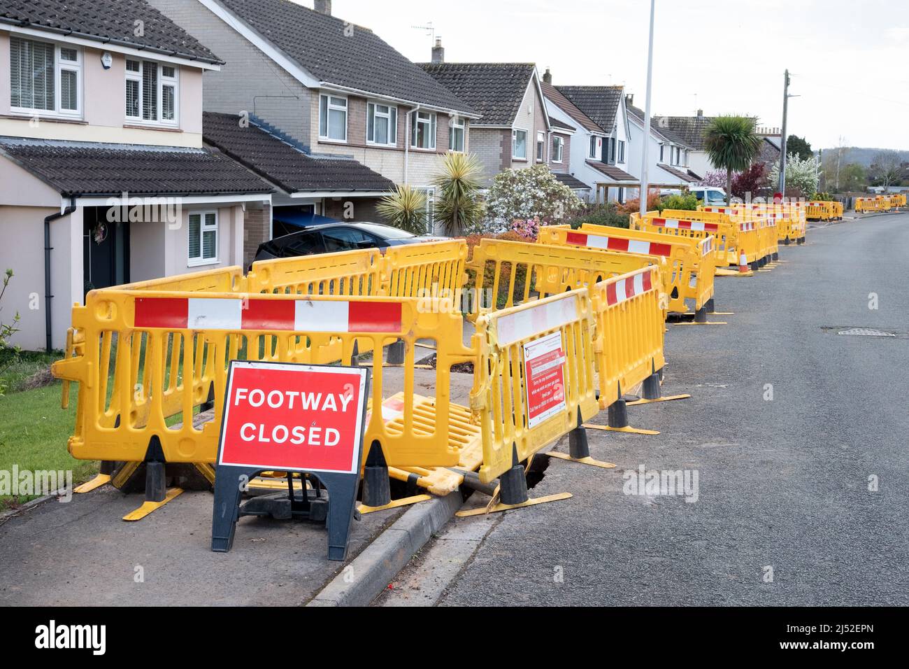 Eine lange Reihe von Kunststoffbarrieren entlang eines geschlossenen Gehwegs, während Wales und West Utilities an der Modernisierung der Gasversorgung von Häusern mit Kunststoffrohren arbeiten Stockfoto