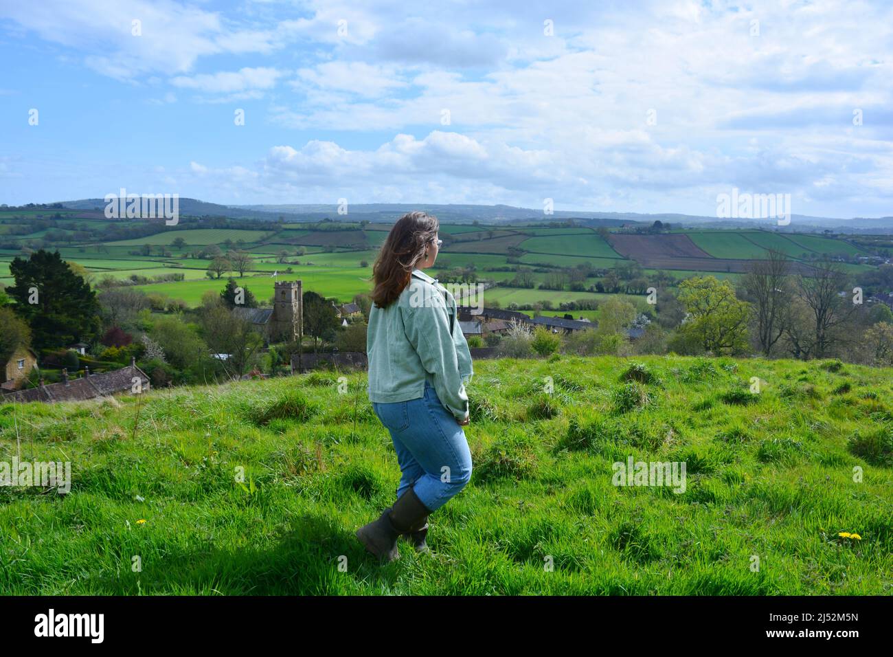 Frau, die im Frühling, Großbritannien, auf einem Hügel mit Blick auf die wunderschöne Landschaft von Somerset spazierengeht Stockfoto