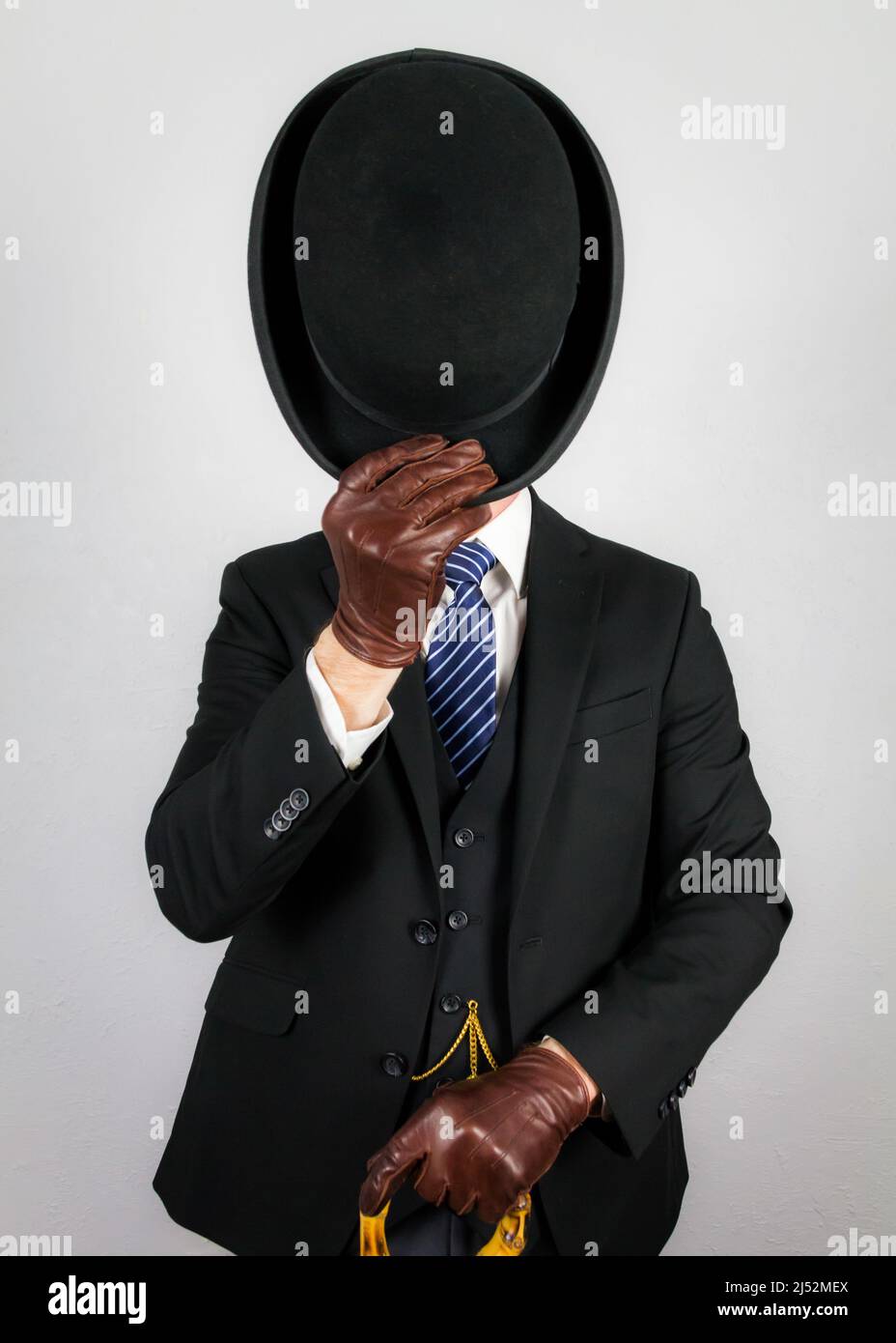 Porträt des britischen Butlers in dunklem Anzug elegant doffing Bowler Hut in höflicher Begrüßung. Vintage Style des englischen Gentleman. Stockfoto