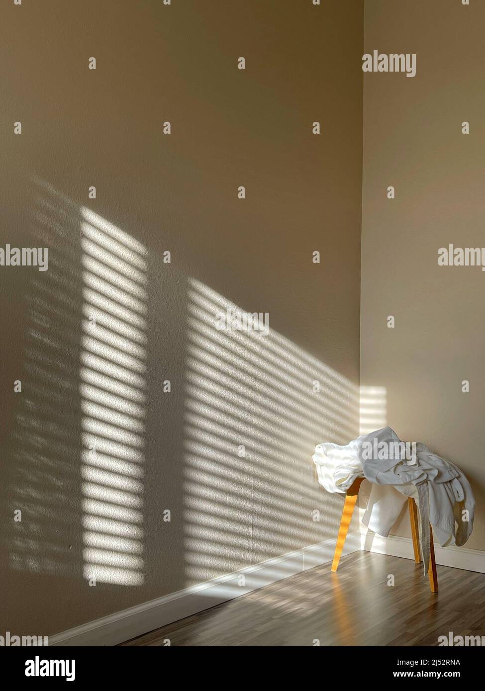 Morgenmantel auf einem Hocker mit Sonneneinstrahlung durch die Fensterläden Stockfoto