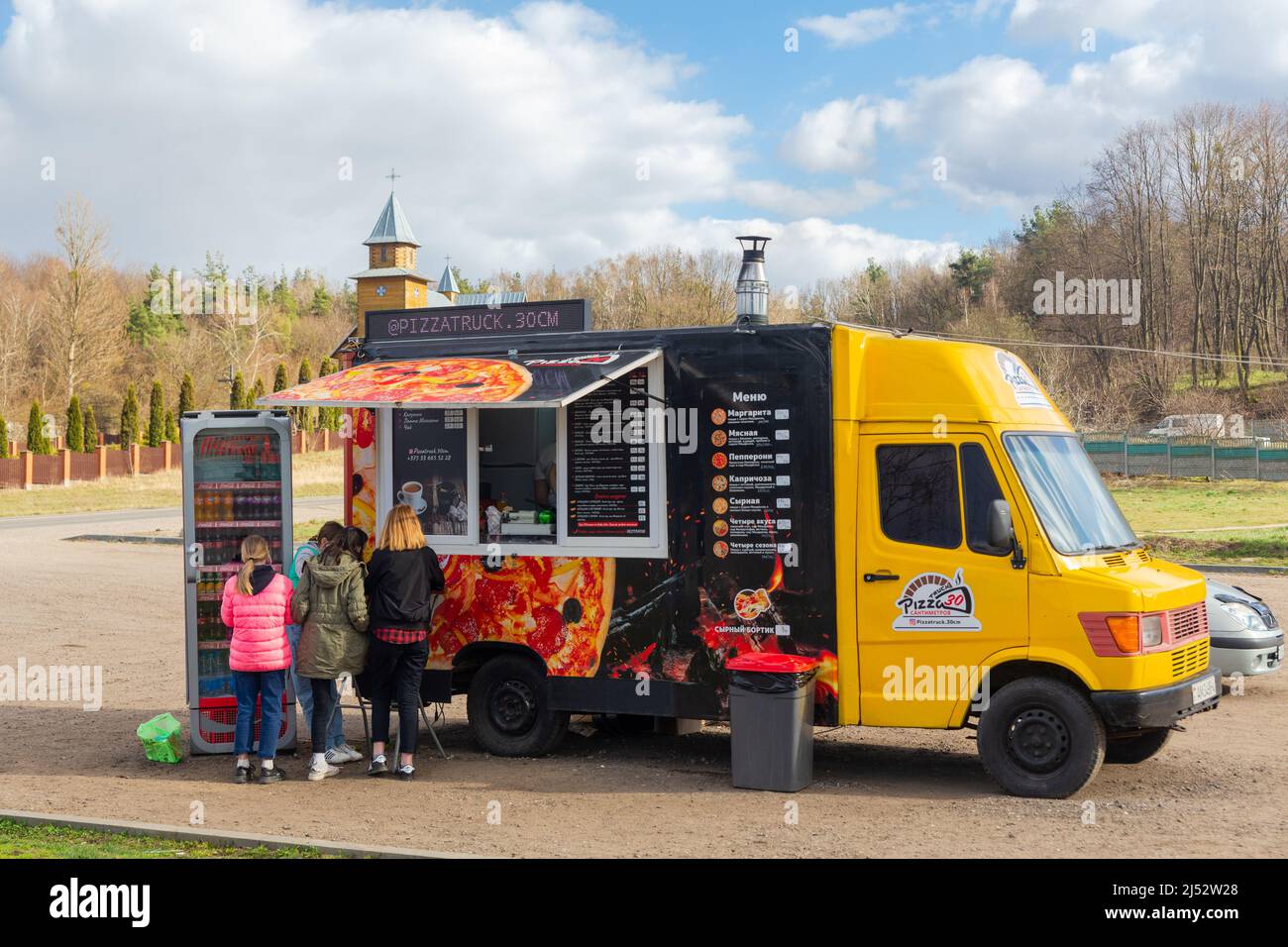 Putrishki, Weißrussland - 17. April 2022: Die Leute bestellen an einem Pizzawagen in der Nähe der Straße. Eine Pizzeria auf Rädern kocht Pizza in einem installe Ofen Stockfoto