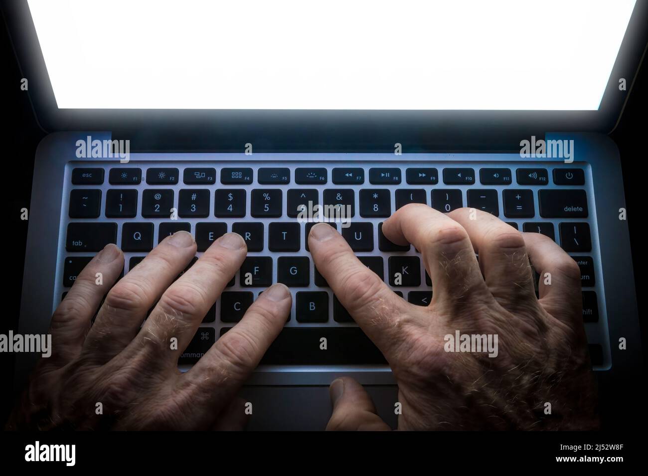 Detail der Handeingabe auf der Computertastatur mit leuchtendem Bildschirm Stockfoto