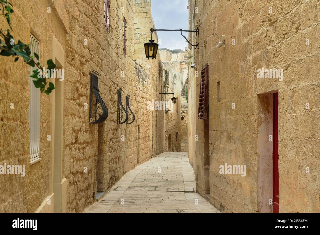 Mdina, Malta Leere Gasse entlang aus Stein gebauten Häusern in mittelalterlichen historischen Stille Stadt gepflastert mit Steinplatten & Kalksteinmauern mit hängenden Laternen. Stockfoto