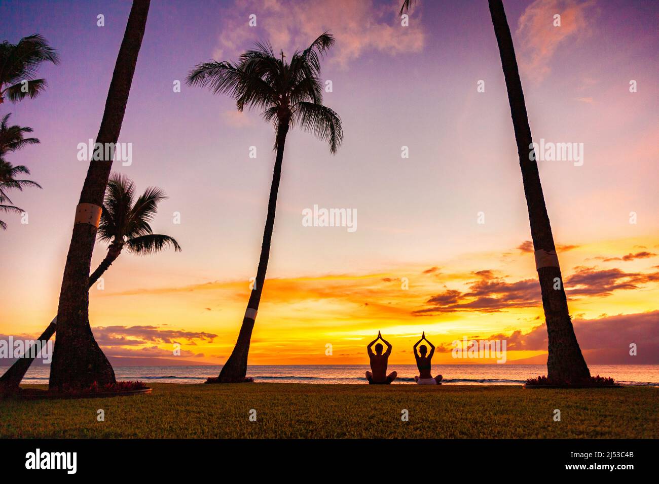 Yoga-Retreat auf tropischer Sommerferienmeditation Menschen meditieren in Lotuspose mit betenden Händen in Sonnenuntergangs-Glow-Silhouetten am Strand Stockfoto