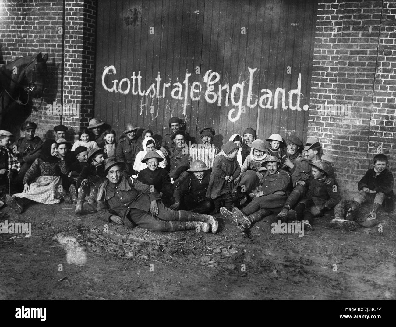 Soldaten und Einheimische vor einem Gebäude mit deutschen Graffiti, während des Ersten Weltkriegs.die Tür des Gebäudes ist mit "Gott strafe England", d.h. "Gott bestrafe England", übertünchen. Stockfoto