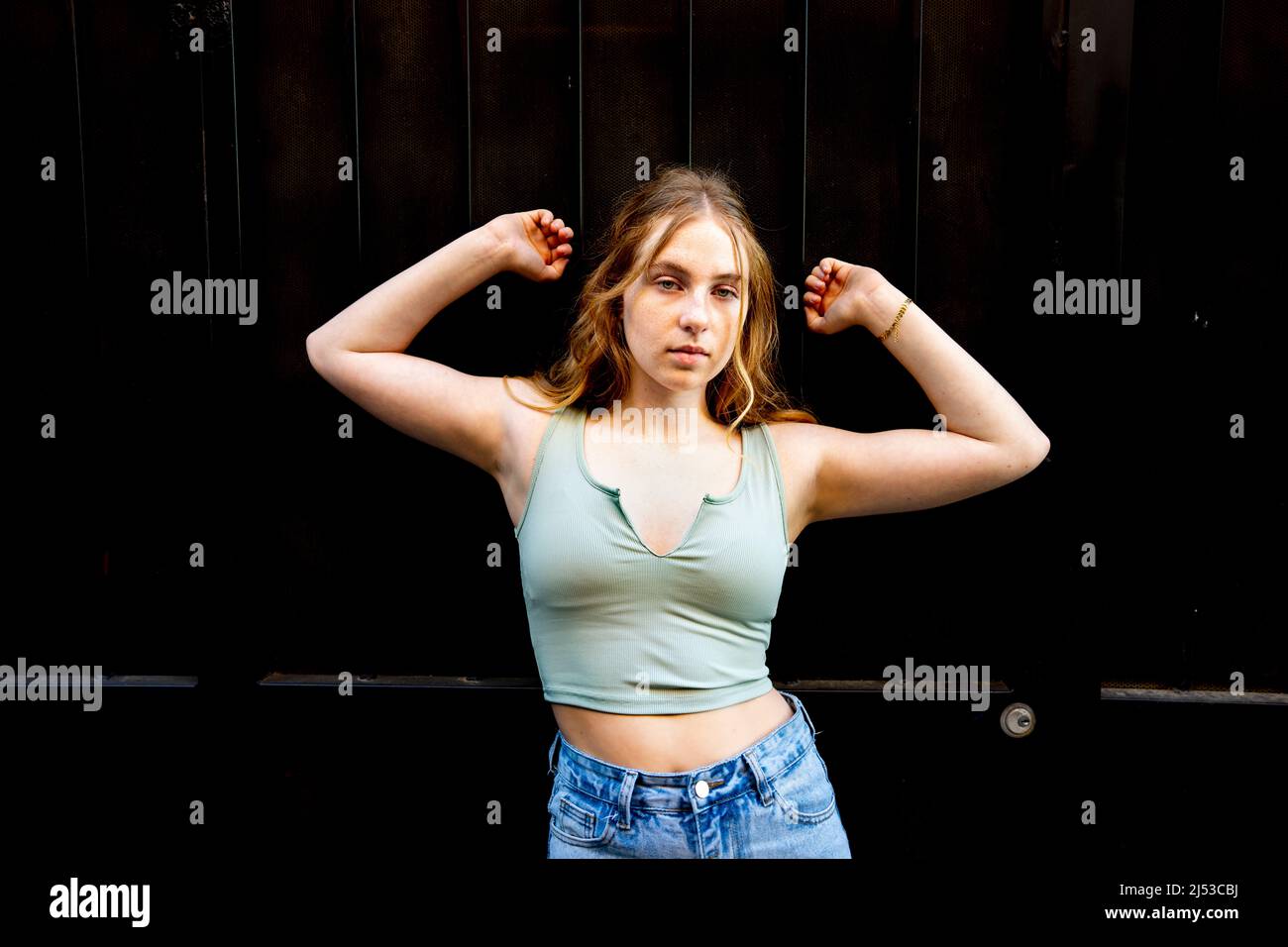 Junge Frau, die in der Altstadt von Sacramento gegen die Mauer steht Stockfoto