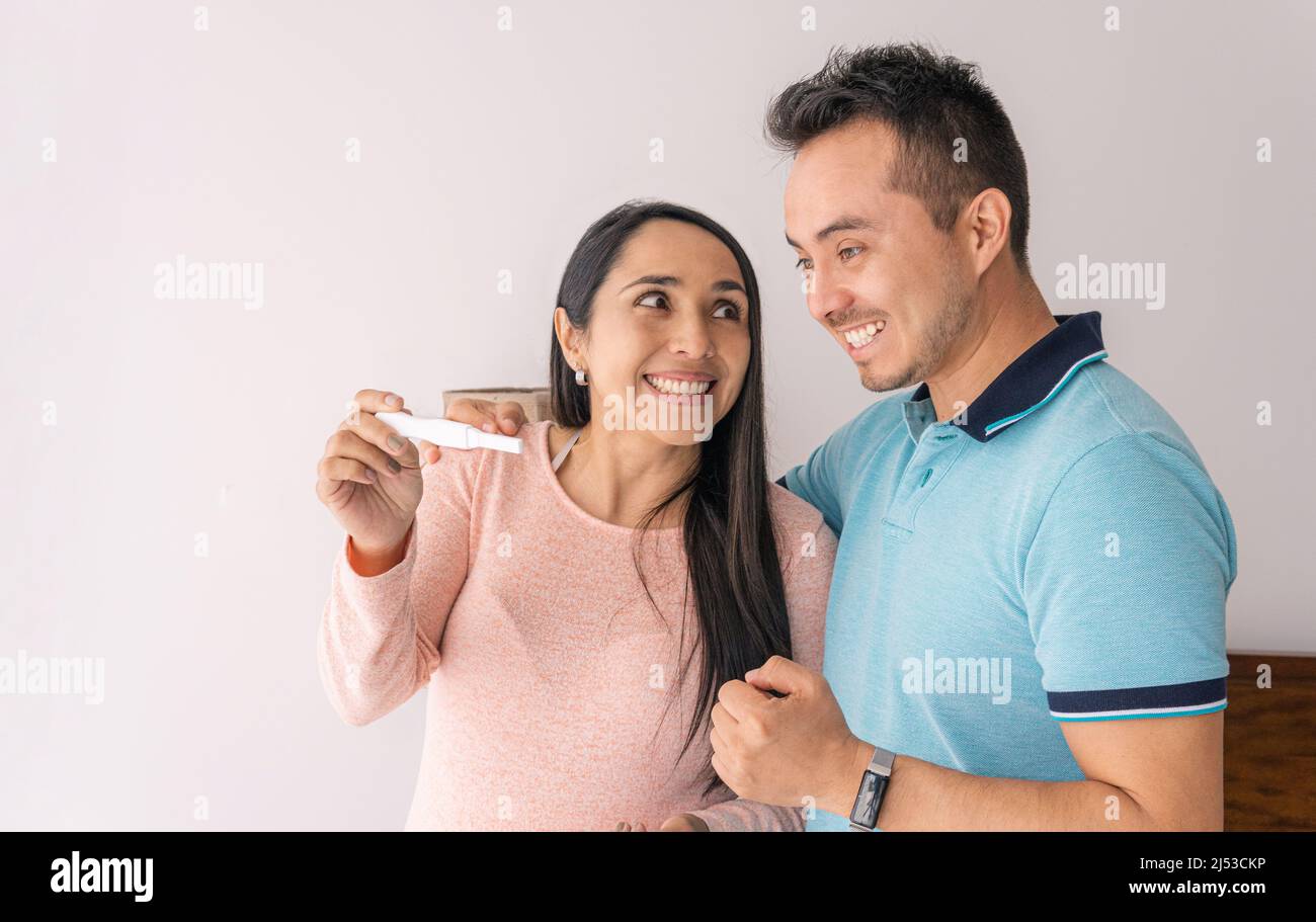 Aufgeregtes Paar, das zu Hause ein positives Ergebnis des Schwangerschaftstests ansieht Stockfoto