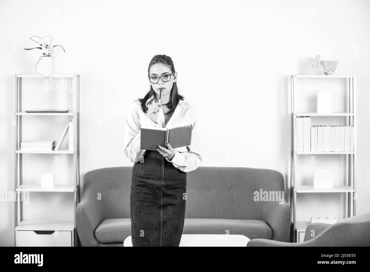 Denkende Studentin Porträt einer jungen Geschäftsfrau Buchhalterin in formeller Kleidung mit Notizbuch oder Notizblock am Büroarbeitsplatz. Erfolgreiche Managerin Stockfoto