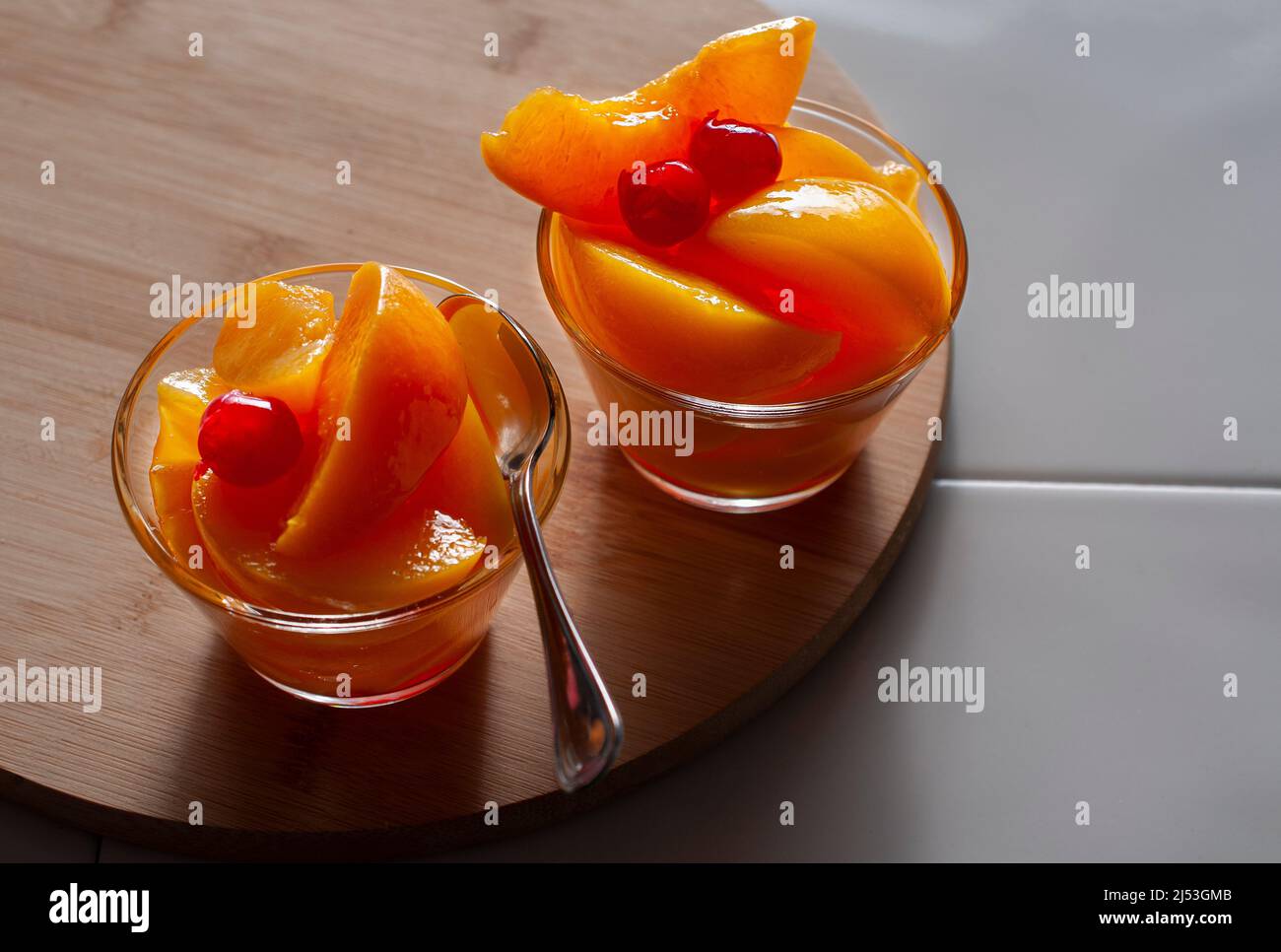 In Sirup geschnittene Pfirsiche mit Kirschen auf einem Holzbrett. Stockfoto