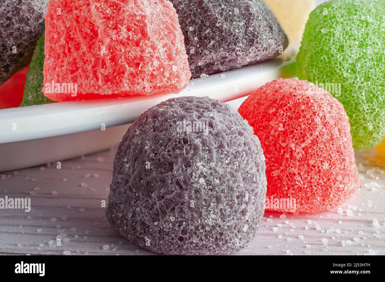 Süßigkeiten, Gummys in verschiedenen Geschmacksrichtungen und Farben auf einem weißen Teller und einem weißen Tisch. Makrofotografie Stockfoto