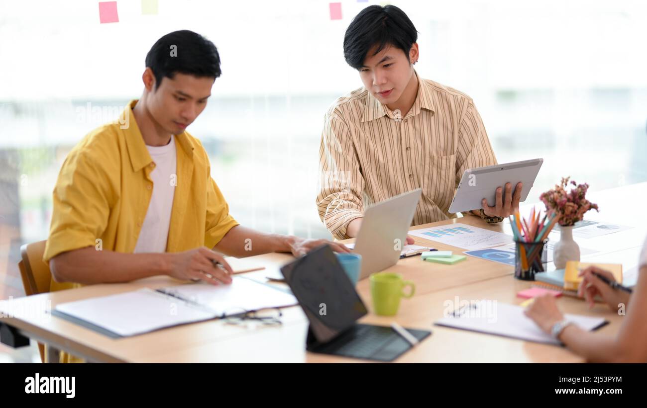 Asiatische junge männliche Mitarbeiter, die gemeinsam an dem Projekt arbeiten und die Aufgabe im Büro Brainstorming durchführen. Stockfoto