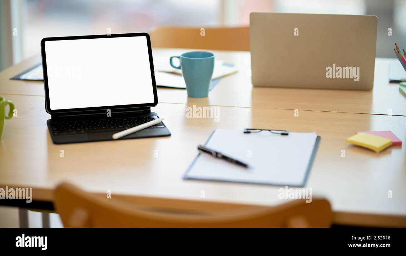 Nahaufnahme, Büroarbeitsplatz mit tragbarem, weißem Tablet-PC-Modell und kabellosem Tastaturständer auf dem Tisch mit Zwischenablage und Büromaterial. Stockfoto