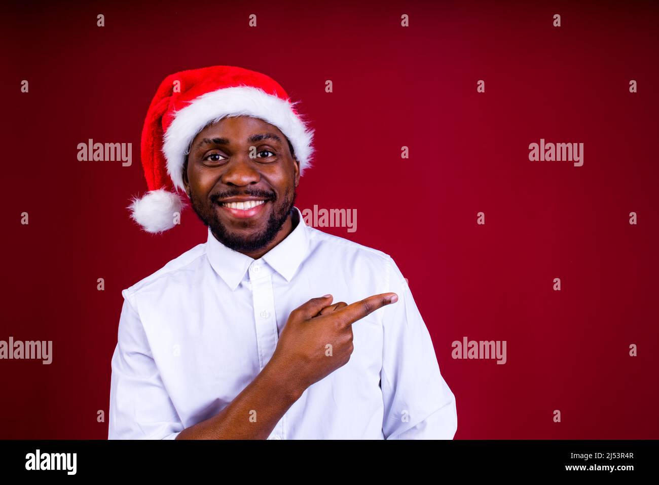 brasilianischer Mann tragen weihnachtsmann Kopfbedeckung isoliert über roten Hintergrund Stockfoto