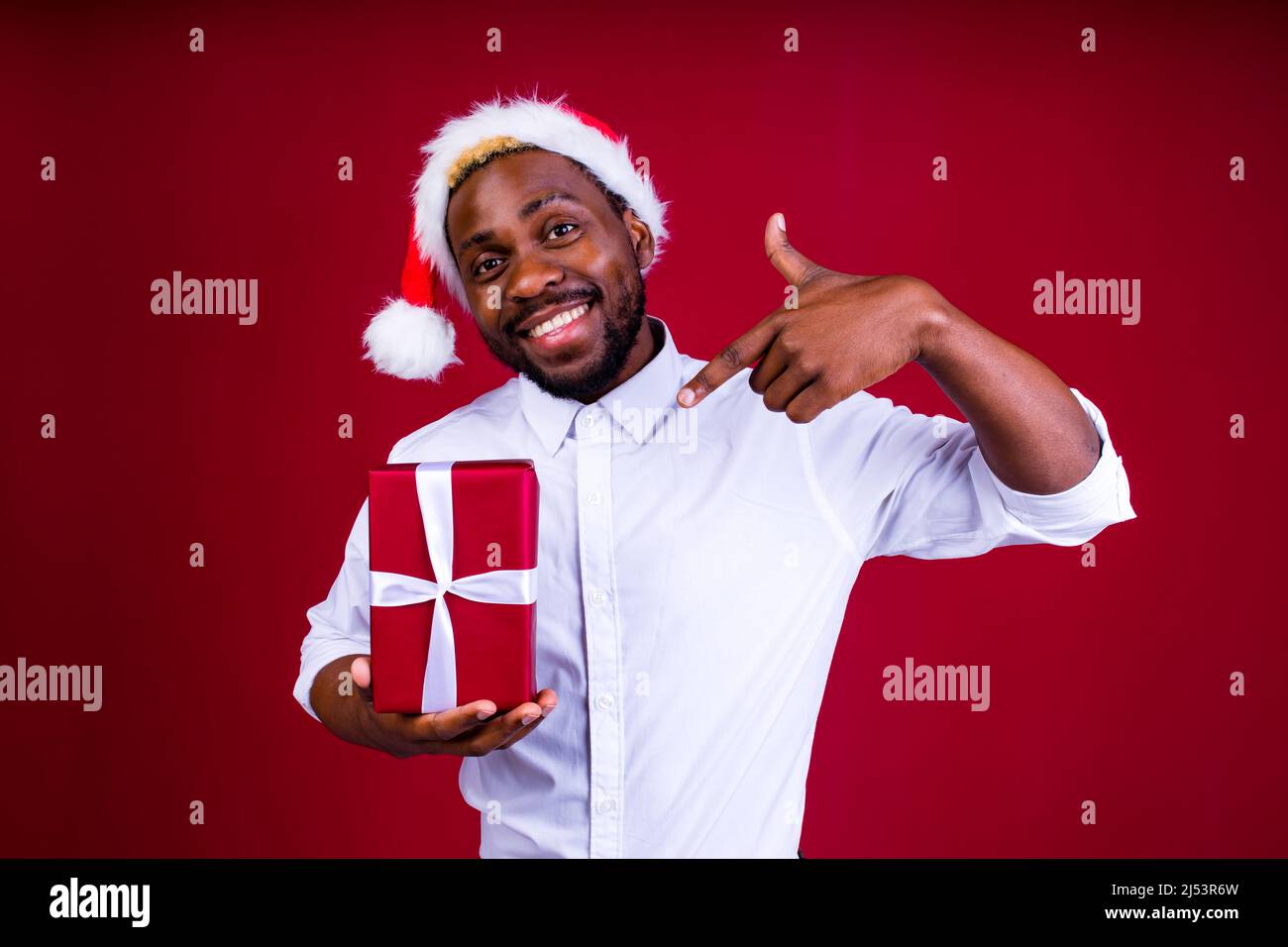 lateinamerikanischer mann mit weihnachtsmütze auf Studio-rotem Hintergrund Stockfoto