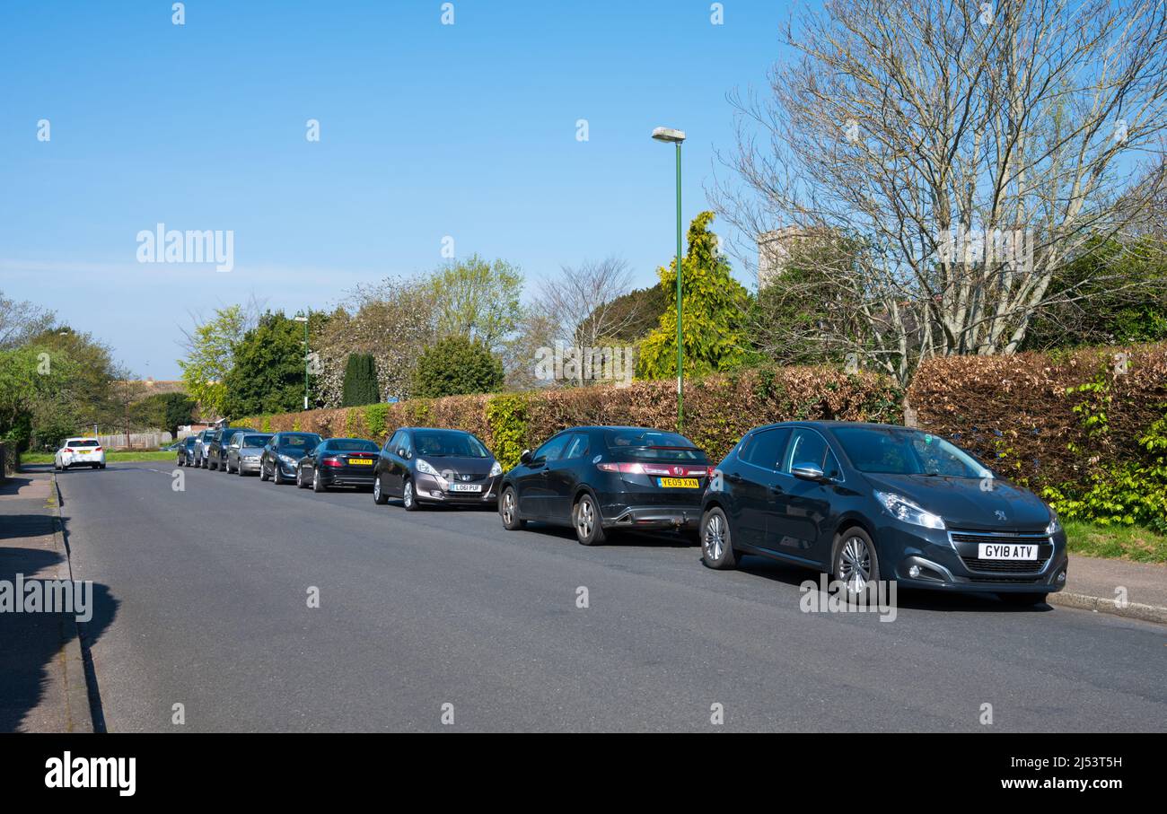 Reihe oder Reihe geparkter Autos, um das Parken auf der Straße oder das Parken auf der Straße in England, Großbritannien, zu veranschaulichen. Stockfoto