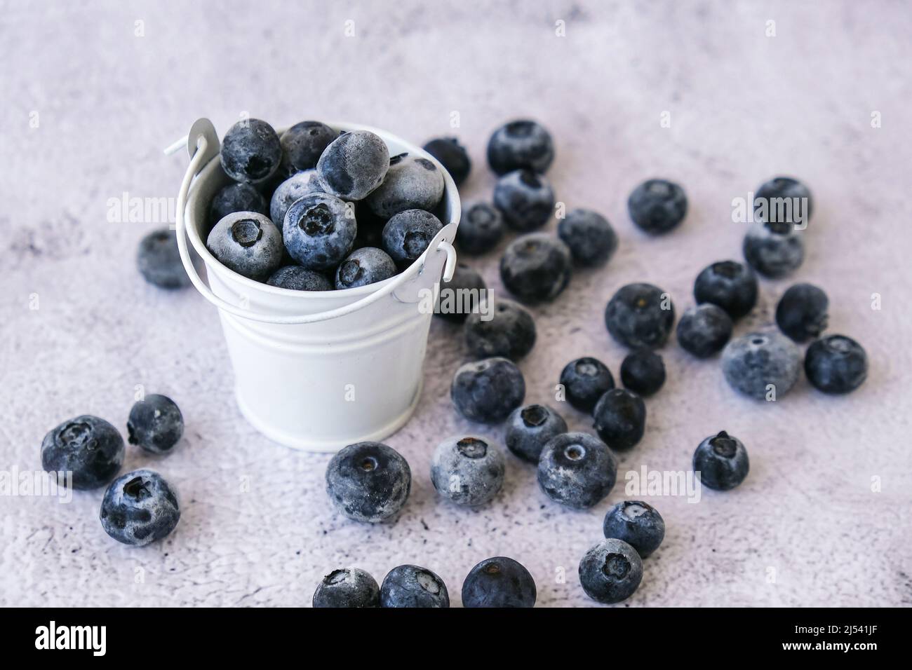 Gefrorene Heidelbeeren in einem kleinen Eimer auf Betongrund. Gesunde Bio saisonalen Obst Hintergrund. Bio-Lebensmittel. Ernte, Zubereitung von Lebensmitteln für den Sieg Stockfoto