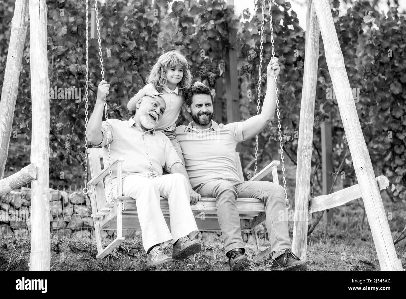 Aufgeregt Großvater Vater und Sohn spielen im Freien, sitzen auf der Schaukel. Glückliche Männer Familie. Drei-Mann-Generation. Stockfoto