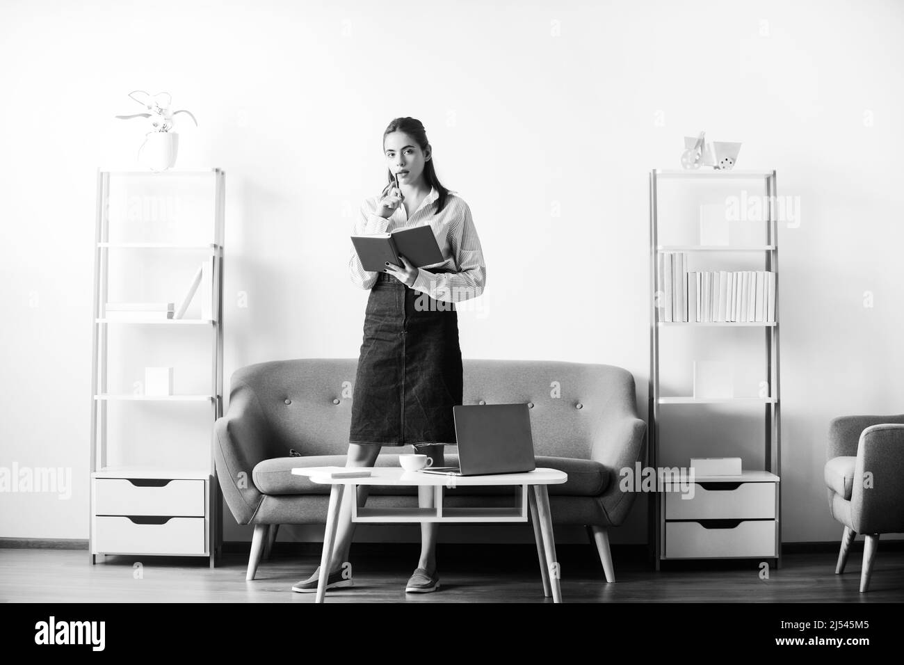 Junge attraktive Sekretärin Frau an einem geschäftigen modernen Arbeitsplatz im Büro. Hübsches Buchhalterin Mädchen am Schreibtisch im Büroinneren. Stockfoto