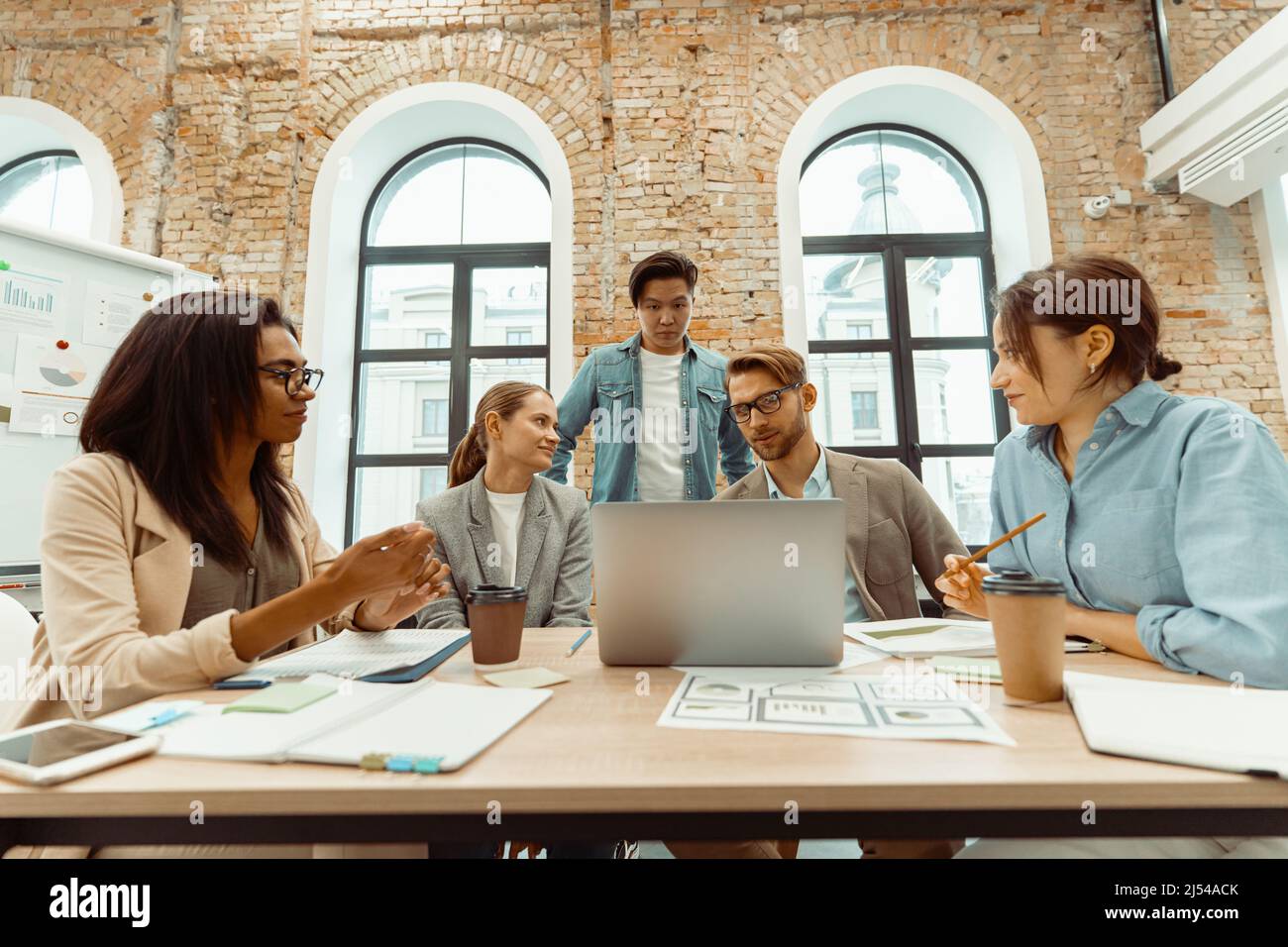 Junge Leute, die im Büro auf Laptop-sreen schauen Stockfoto