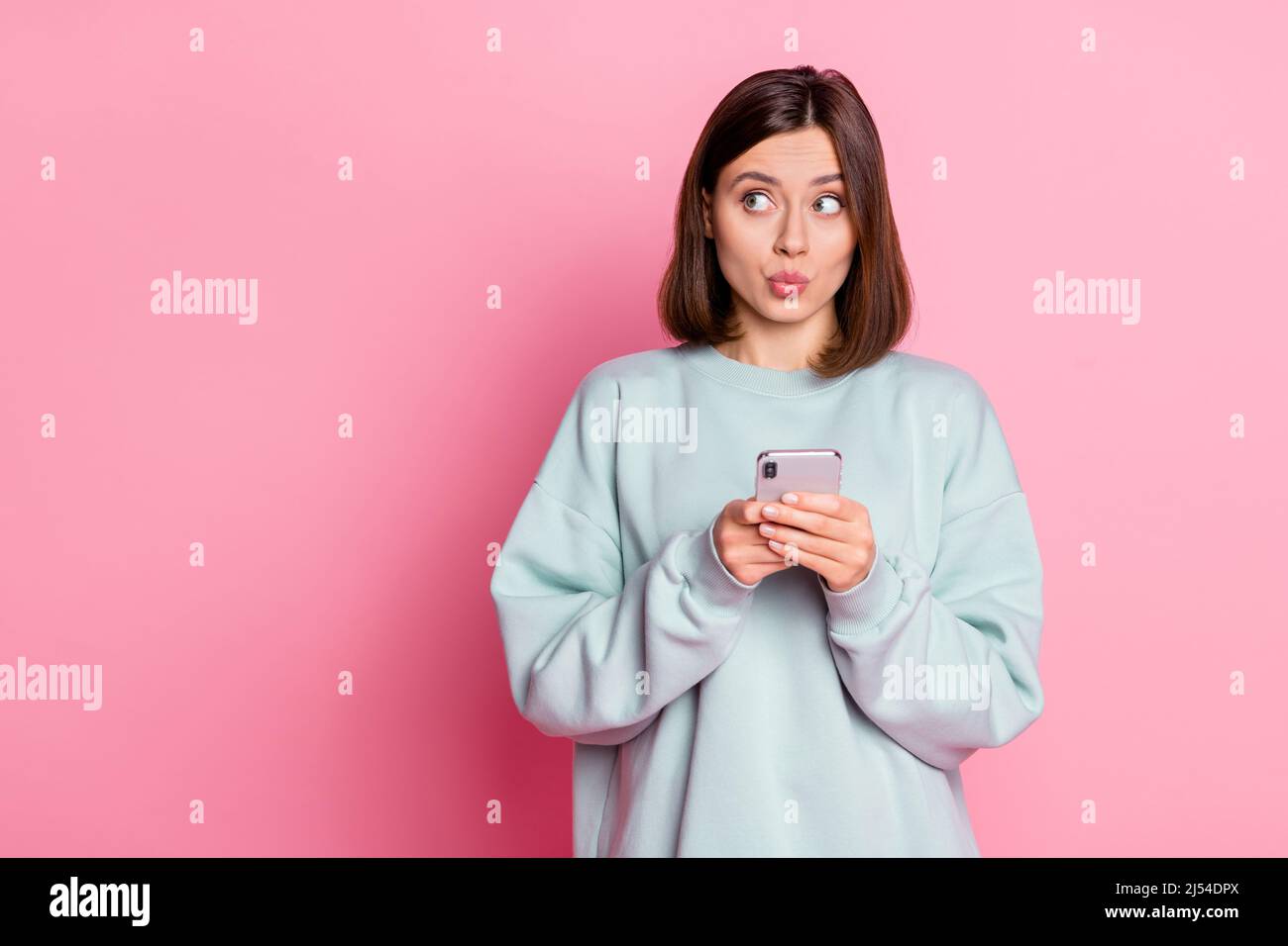 Foto von jungen hübschen Mädchen denken, schauen leer Raum Plan verwenden Smartphone isoliert über rosa Hintergrund Stockfoto