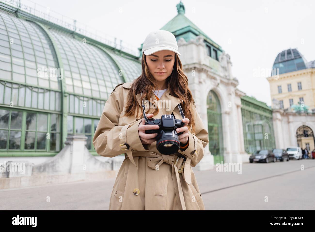 Fotograf in Trenchcoat und Baseballmütze mit Digitalkamera in der europäischen Stadt Stockfoto