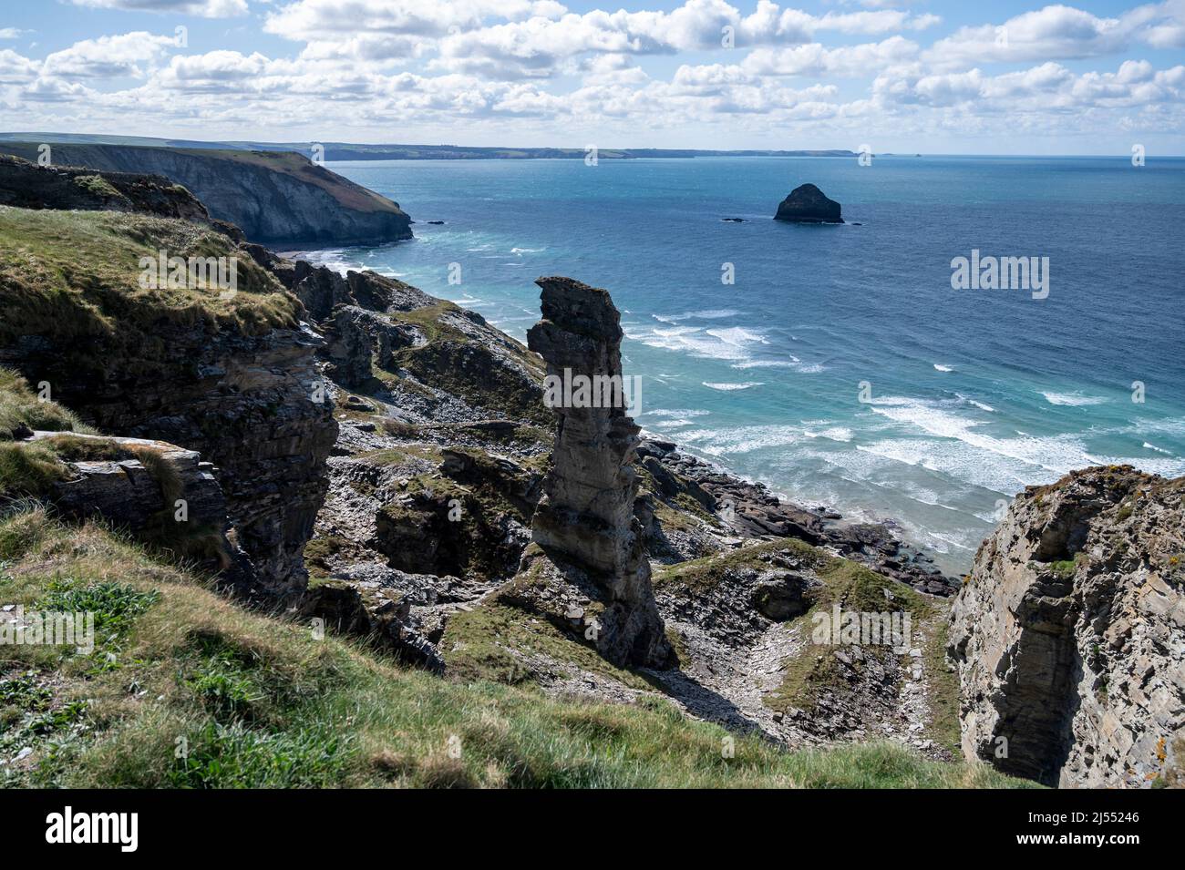 Ein prominenter Schieferstapel aus dem historischen Lanterdan Quaries auf dem South West Coast Path mit blauem Meer, Klippen und Gull Rock. Stockfoto