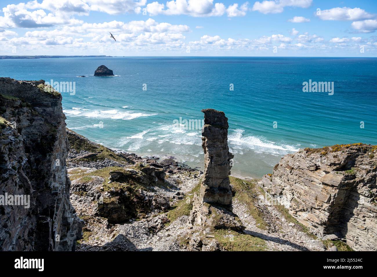 Ein prominenter Schieferstapel aus dem historischen Lanterdan Quaries auf dem South West Coast Path mit blauem Meer, Klippen und Gull Rock. Stockfoto