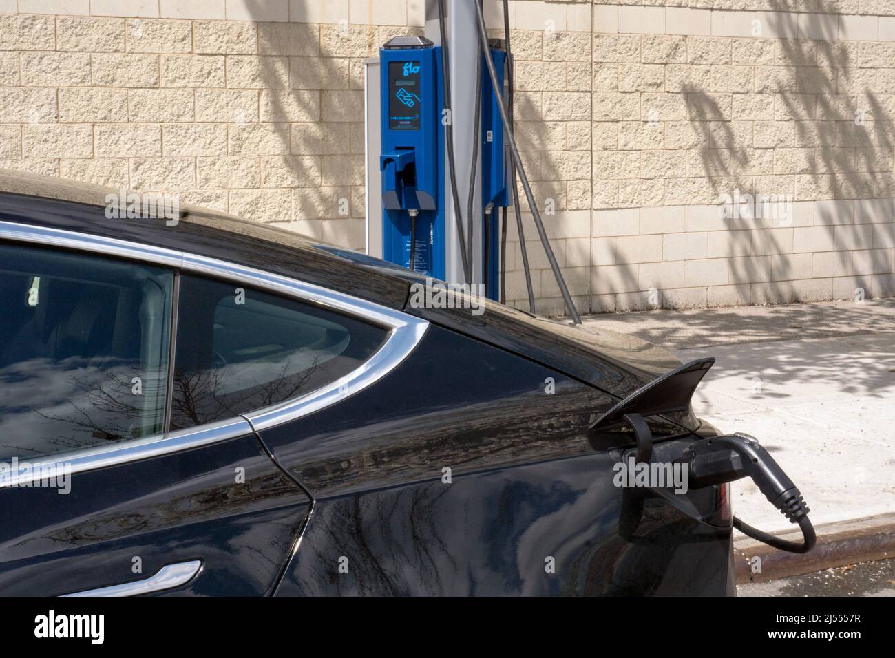 Ein Tesla-Elektroauto lädt seine Batterie an einer FLO-Ladestation in Astoria Queens, New York City. Stockfoto
