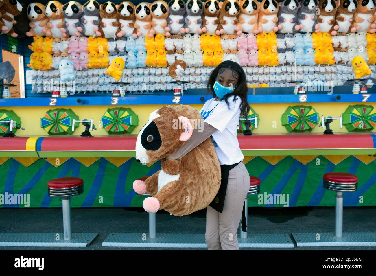 Eine Teenager aus Brooklyn beginnt ihren Sommerjob, indem sie an den Frühlingswochenenden an einem Geschicklichsspiel im Luna Park arbeitet. In Coney Island, Brooklyn, New York City. Stockfoto