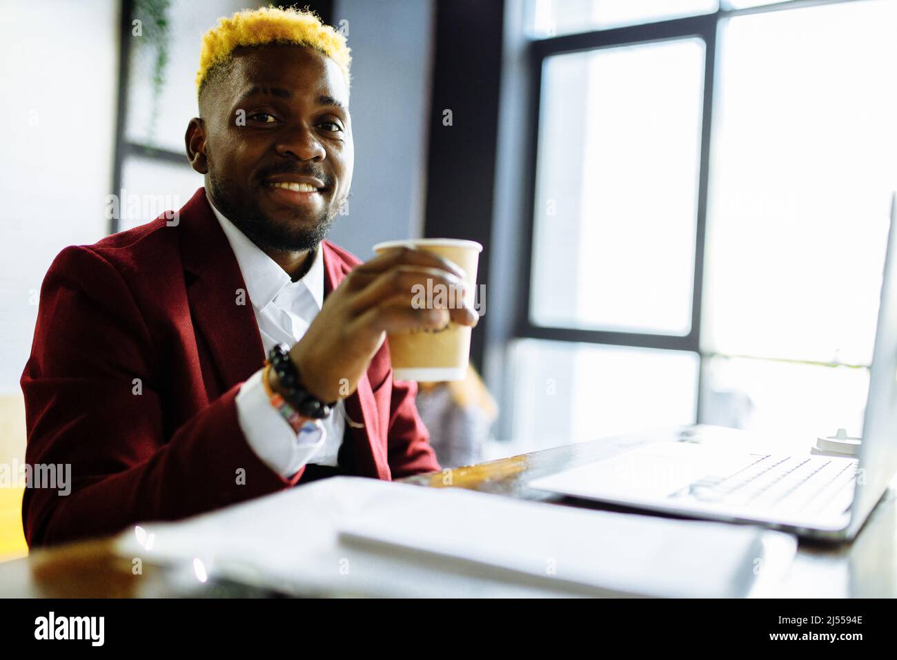 afro-amerikanischer Mann in der marsala Jacke Fernarbeit im Wohnzimmer zu Hause Stockfoto