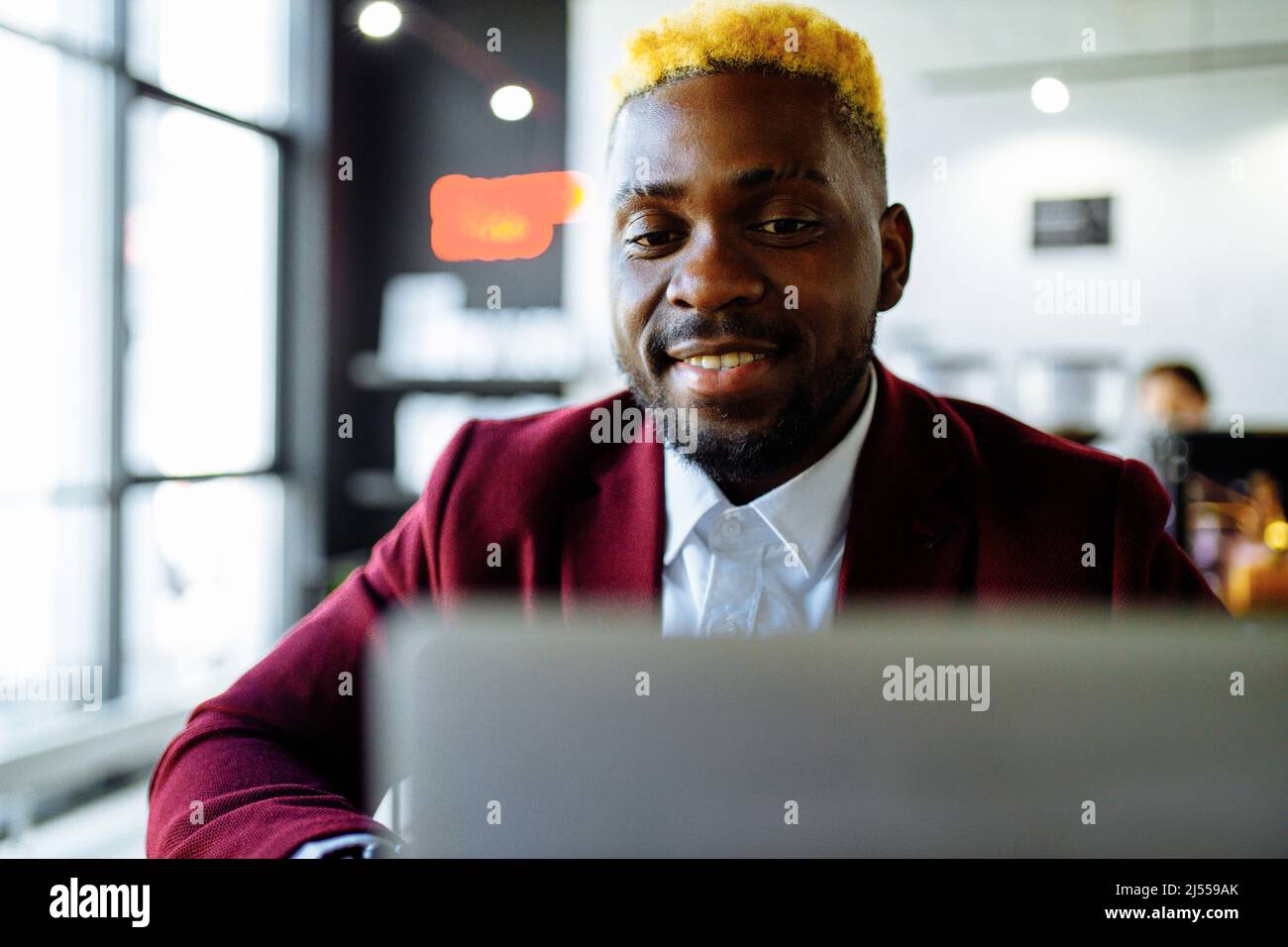 afro-amerikanischer Mann in der marsala Jacke Fernarbeit im Wohnzimmer zu Hause Stockfoto