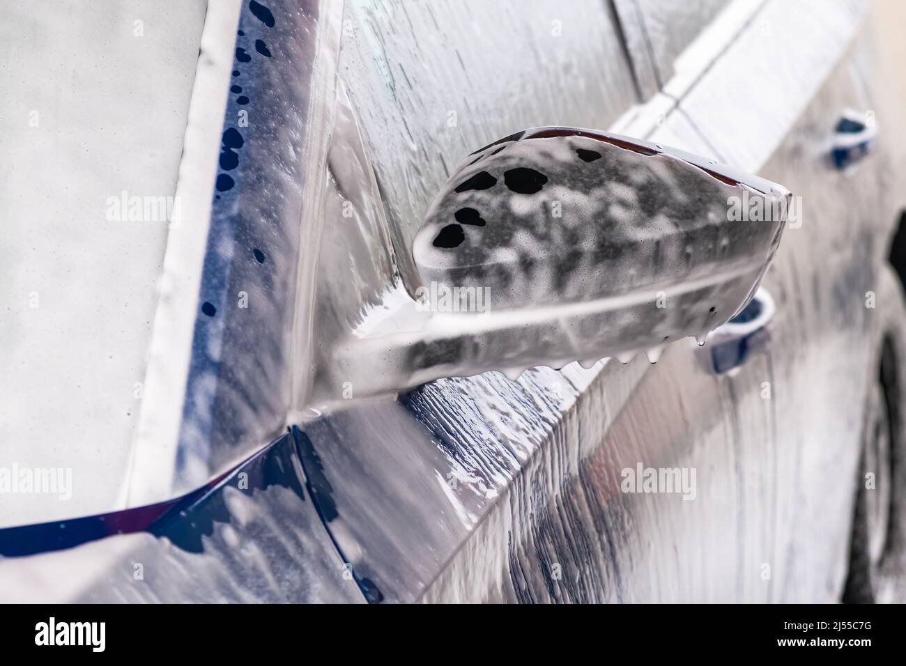 Reinigung des blauen Automobils mit Seife und Druckwasserstrahl bei der Autowaschanlage. Elektrofahrzeug in Garage gewaschen Nahansicht Stockfoto