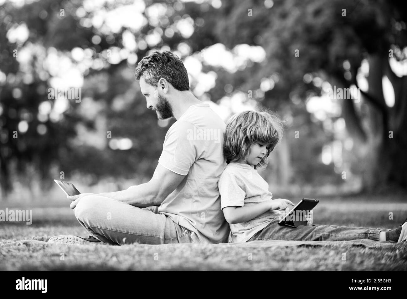 Fernunterricht im Freien. Vater mit Laptop Entspannen Sie sich mit Schüler Sohn halten Laptop viel Spaß zusammen. Familie mit Gadgets draußen auf die Natur. Stockfoto