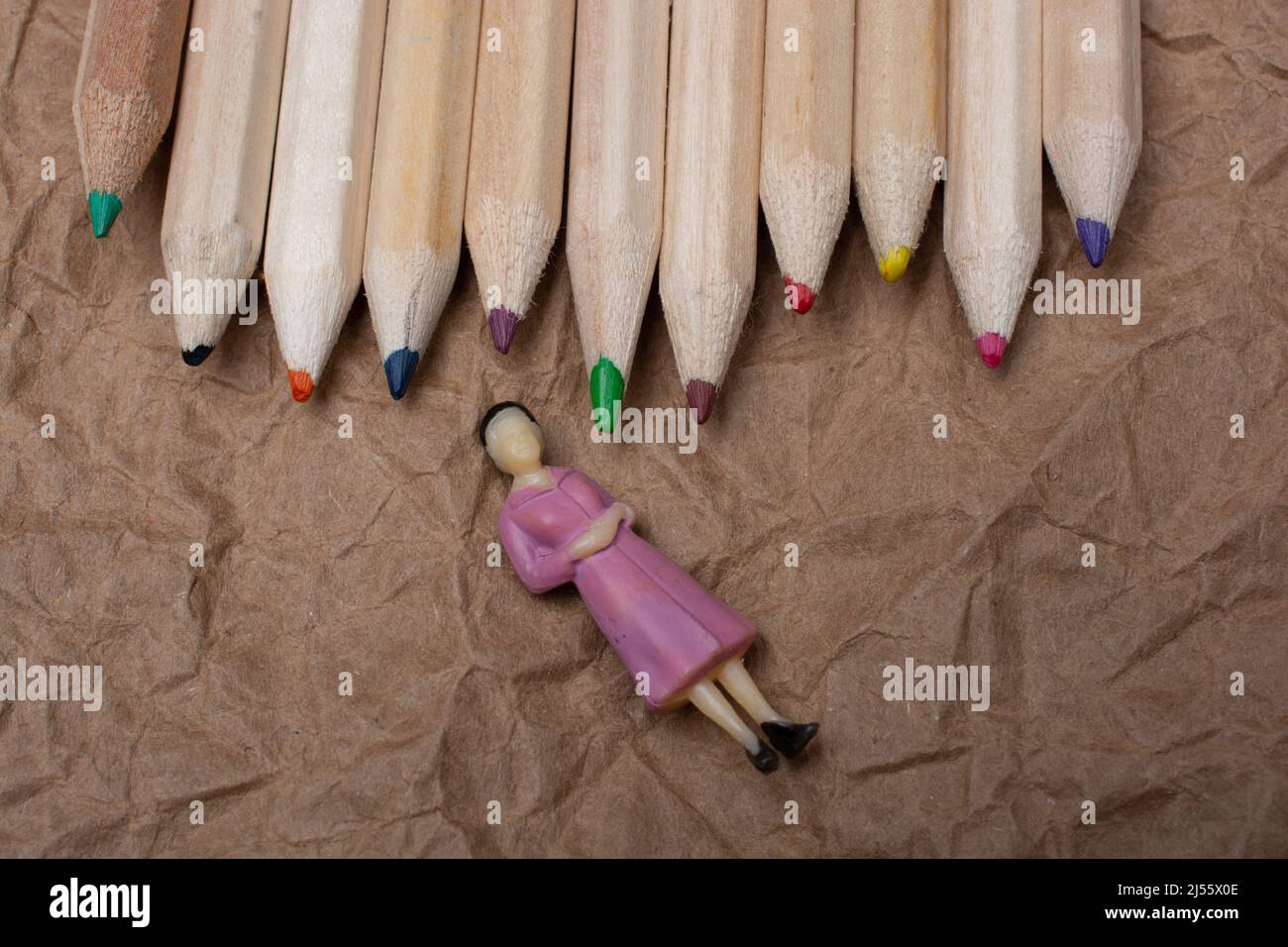 Buntstifte auf Papierhintergrund mit einer Frauenfigur Stockfoto